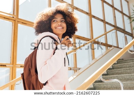 Smiling girl looking back while standing on stairs in school. Student going for the lecture. Royalty-Free Stock Photo #2162607225