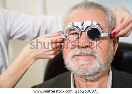 making a selection of lenses, diagnosing a elderly man's vision on a sign projector. modern medical device. advertising of the clinic, treatment and correction of vision.