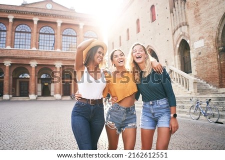 Fantastic time spent with best friends. Three happy girls having fun outdoors in summer vacations at city. Portrait of smiling woman hugging looking at camera together Royalty-Free Stock Photo #2162612551