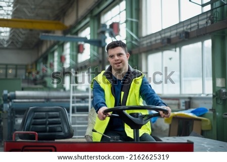 Young man with Down syndrome working in industrial factory, social integration concept. Royalty-Free Stock Photo #2162625319