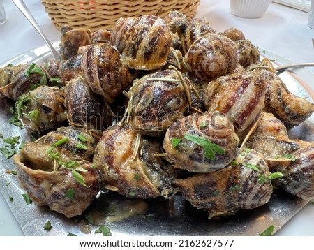 Closeup image of a dish of Cretan snails with olive oil and fresh herbs. Royalty-Free Stock Photo #2162627577
