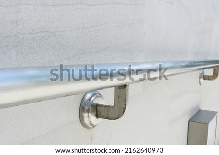 Close-up steel railing structure installed on granite tile wall. Royalty-Free Stock Photo #2162640973