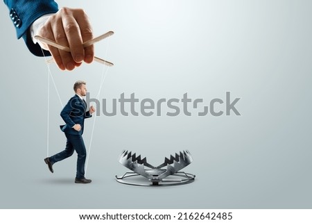 A man's hand leads a puppet into a trap. The concept of mortgage, dirty money, bribe, corruption, easy money, debt, credit. mixed media Royalty-Free Stock Photo #2162642485