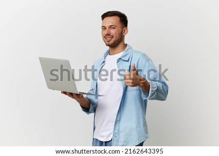 Joyful smiling tanned handsome IT professional man in casual basic t-shirt hold laptop show thumb up posing isolated on white studio background. Copy space Banner Mockup. Electronics repair concept