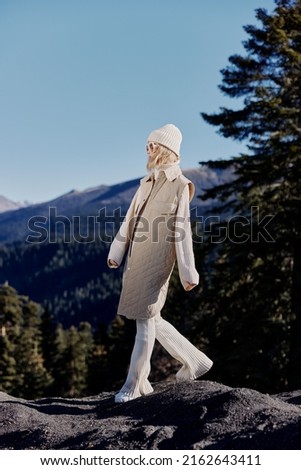 young woman in autumn clothes stands on a rock blue sky relaxation