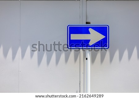 White wall and blue one-way sign