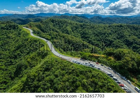Many cars have parked in the parking area at the zigzag road is similar to the number 3. This road is built on a mountain, past the forest in Nan, Thailand.