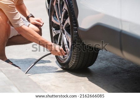 man driver hand inflating tires of vehicle, removing tire valve nitrogen cap for checking air pressure and filling air on car wheel at gas station. self service, maintenance and safety Royalty-Free Stock Photo #2162666085