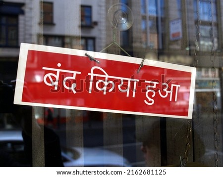 Closed sign in a shop window written in Hindi (translation: Closed)