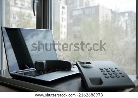 Modern laptop and telephone handset, close up image. on office window background.  Computer Phone. Video Internet.