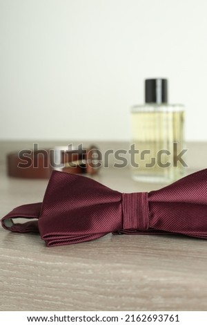 Stylish burgundy bow tie on wooden table, closeup