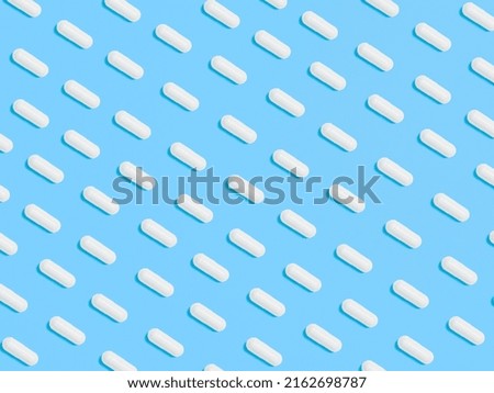 Pattern from Pills, tablets, vitamins, food supplement in white capsules on blue background. Health concept, vitamin deficiency, avitaminosis, medical pharmaceutical background. Flat lay top view