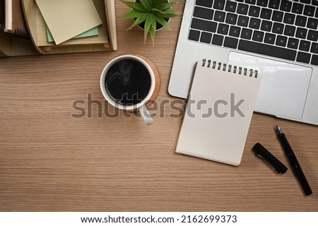 Laptop computer, blank notepad, pen and coffee cup on wooden tale. Flat lay, Top view