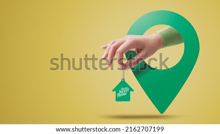 Hand holding house shaped keychain and location pin, real estate concept Royalty-Free Stock Photo #2162707199