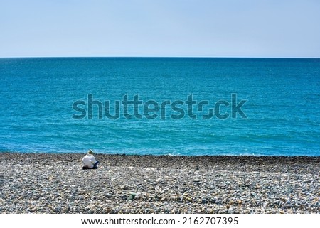 Lonely woman sitting on the beach near the sea