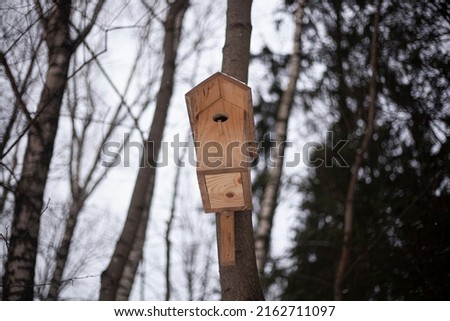Birdhouse on the tree. A feeder attached to a tree trunk. Birdhouse for wintering feathered creatures. Cold weather food in a special house for the winged.