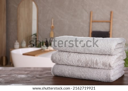 White clean towels on wooden table in bathroom. Space for text Royalty-Free Stock Photo #2162719921
