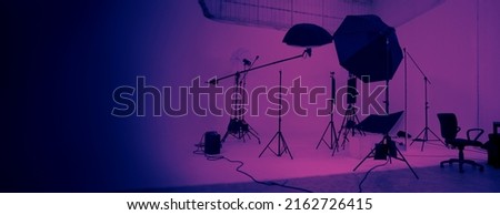Studio video production lighting set. Behind the scenes shooting production set up by crew team camera and equipment in studio. Video production filming or commercial movie film live streaming online. Royalty-Free Stock Photo #2162726415