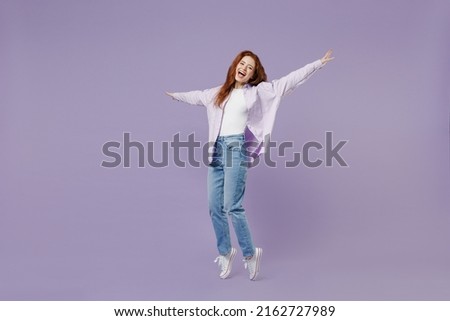 Full size body length young redhead curly woman 20s wear white T-shirt violet jacket stand on toes dance lean back have fun spread hands isolated on pastel purple color wall background studio portrait Royalty-Free Stock Photo #2162727989