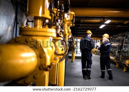 Petrochemical industry, oil and gas production. Factory workers or engineers walking by gas pipelines inside refinery production plant. Royalty-Free Stock Photo #2162729077