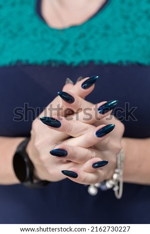 Woman's beautiful hand with long nails and blue and green nail polish