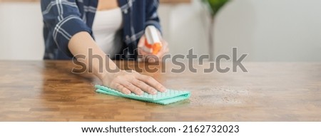 Hand of asian young woman, girl cleaning wood table, use rubs dust, rags ,spray bottle in kitchen at home. Household hygiene cleanup, cleaner people, equipment or tool for cleaning. Royalty-Free Stock Photo #2162732023