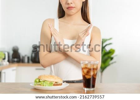 Diet, Dieting hand of asian young woman deny, avoid hamburger, junk or fast food and sparkling water, soft drink, eat food for good healthy, health when hungry. Temptation of weight loss people.