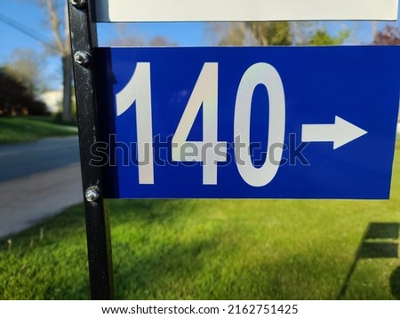 A closeup of the civic sign saying 140 with an arrow pointing in the direction of the address.