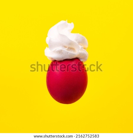 Creative Easter concept with egg and cream. Raspberry egg on a yellow background. Easter dying idea. Minimal Holiday backround. Egg in weightlessness