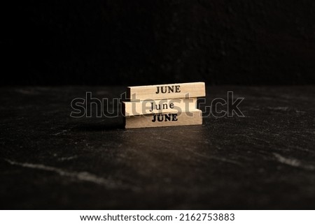 Wooden blocks showing month of June isolated on black marble background