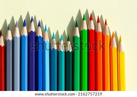 A large number of sharpened colored pencils with falling shadow from natural light on a bright sunny day.