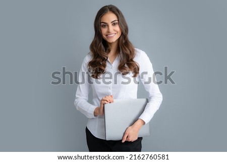 Young beautiful female teacher or happy student isolated on gray studio background. Portrait of college student with laptop. Woman working on laptop, freelance. Royalty-Free Stock Photo #2162760581