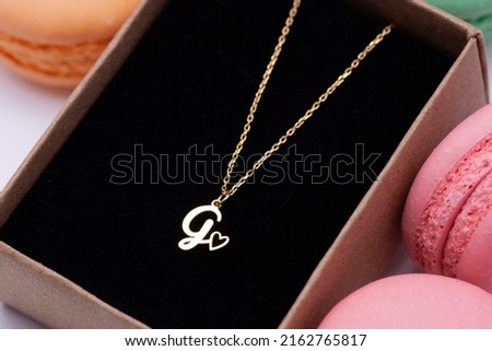 Colorful macarons and silver initial necklace. Image for e-commerce, online selling, social media, jewelry sale.