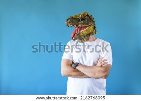 Funny laughing dinosaur head on human body on white t-shirt on blue background, arms crossed and look to the left. Clip art, negative space.