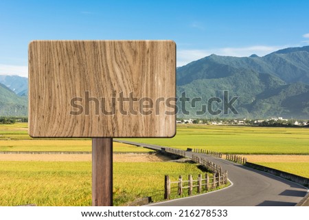 Blank wooden sign on field of farm. Concept of rural, idyllic, tranquility etc.