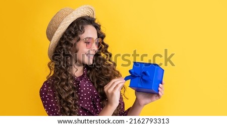 glad kid with curly hair hold present box on yellow background
