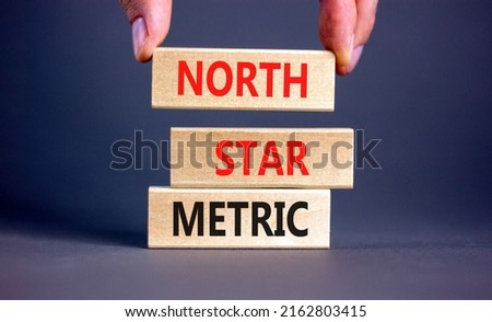 North star metric symbol. Concept words North star metric on wooden blocks on a beautiful grey table grey background. Businessman hand. Business, finacial and north star metric concept. Copy space.