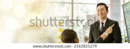 An Asian businessman is presenting his company performance report to his boss or group of male and female colleagues with confidence and professionalism web banner with copy space on left