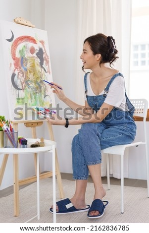 Creative of art concept, Young asian woman using paintbrush with color palette to drawing artwork.