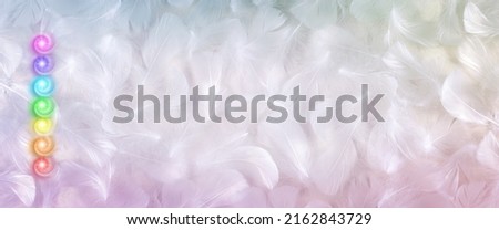 Seven Chakras feather message banner background - pink purple turquoise green yellow orange red vortex energy chakra centres stacked on left side against pale fluffy white feather background  Royalty-Free Stock Photo #2162843729
