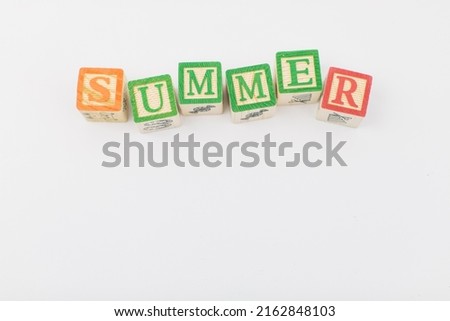 An arrangement of children painted alphabet wooden blocks spelling out "summer" isolated in a white background with text copy space.