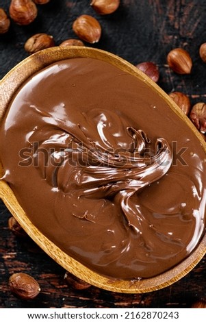 Hazelnut butter with peeled hazelnuts on the table. On a rustic dark background. High quality photo