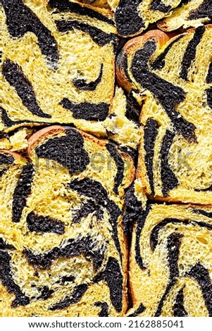 Unusual pumpkin marbled (tiger print) bread with cuttlefish ink, braided on a light background. Useful home baking. Texture laid out from slices of bread.