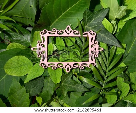 Pastel pink vintage frame against green natural background. Exotic fresh tropic leaves, deep green shades. Summer holiday idea.
