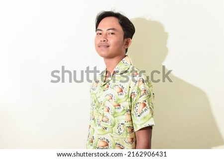 portrait of an Asian man with a happy face, smiling or laughing while looking at the camera. Indonesian man in Hawaiian shirt on white background isolated. stock photos about fashion or traveling