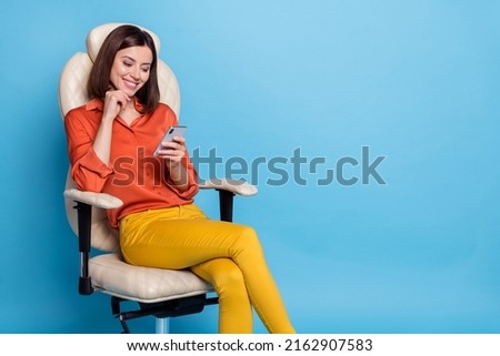Photo of young pretty girl sit armchair use mobile share repost speed connection chat isolated over blue color background