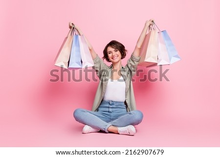 Photo of charming positive lady sit raise packages up enjoy win shopping lottery isolated pastel color background
