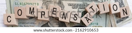 Compensation word written on wood block with American Dollar-bills. Salary and wages concept. Royalty-Free Stock Photo #2162910653