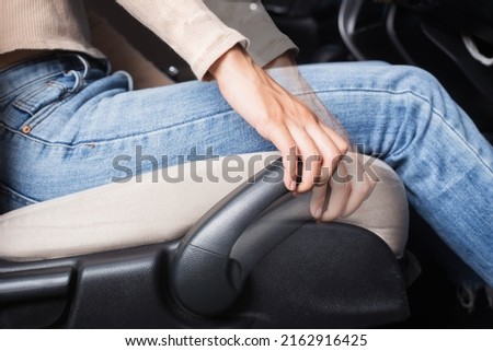 The woman sets up a car driving position. Ergonomic expert adjustment of the driver's seat. Royalty-Free Stock Photo #2162916425