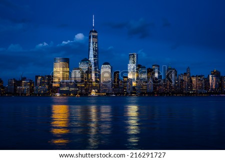 New York City Manhattan downtown skyline with skyscrapers illuminated over Hudson River panorama, including the One World Trade Center